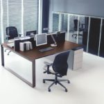 Nowoczesne biuro z ergonomicznymi stanowiskami pracy, ciemnym biurkiem i jasnymi podłogami.