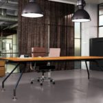Ergonomiczne stanowisko pracy w nowoczesnym biurze z drewnianym biurkiem i szklanymi ścianami.