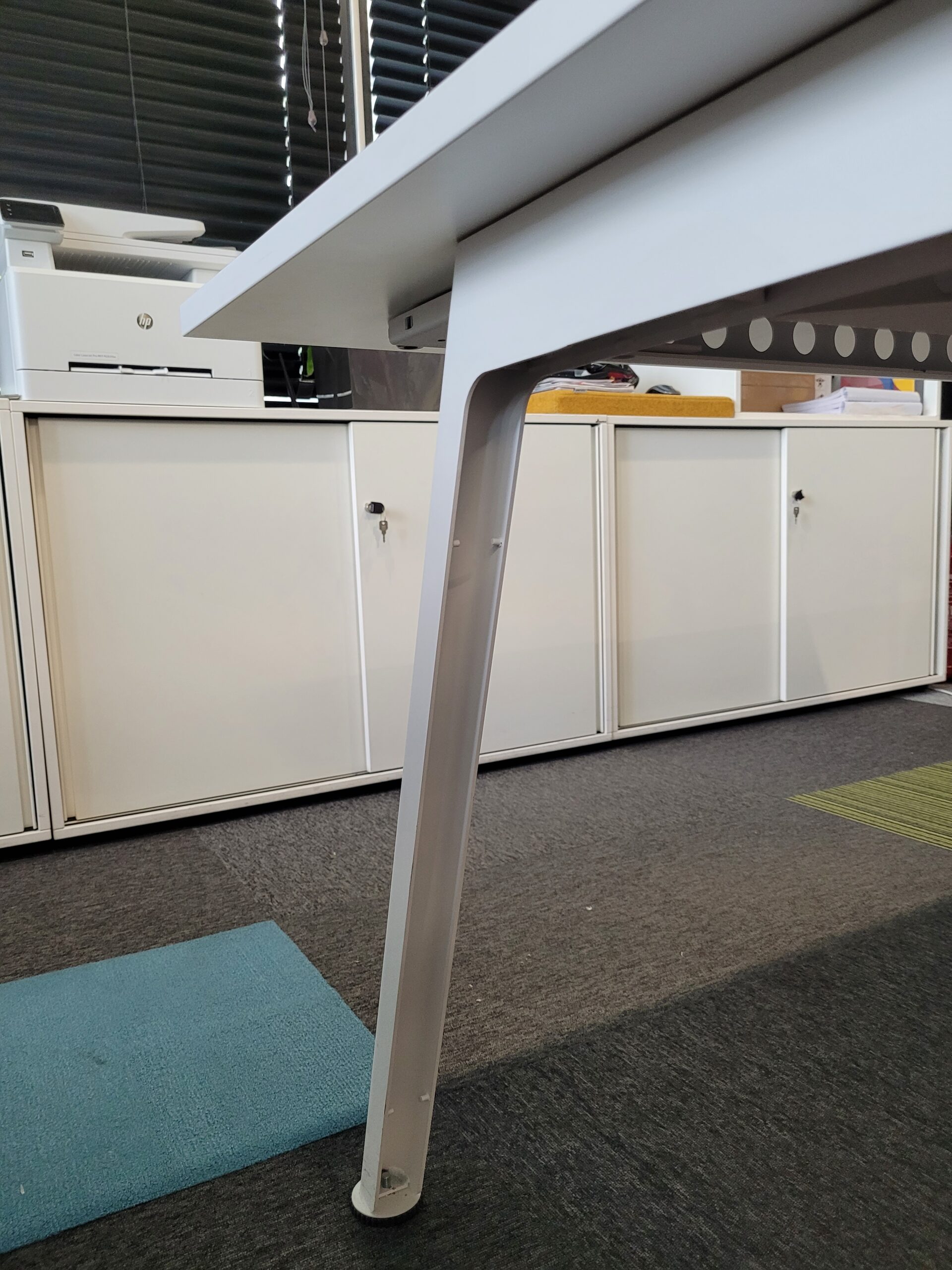 Ergonomiczne biurko i szafki biurowe w funkcjonalnej aranżacji przestrzeni pracy, dominują szarości.