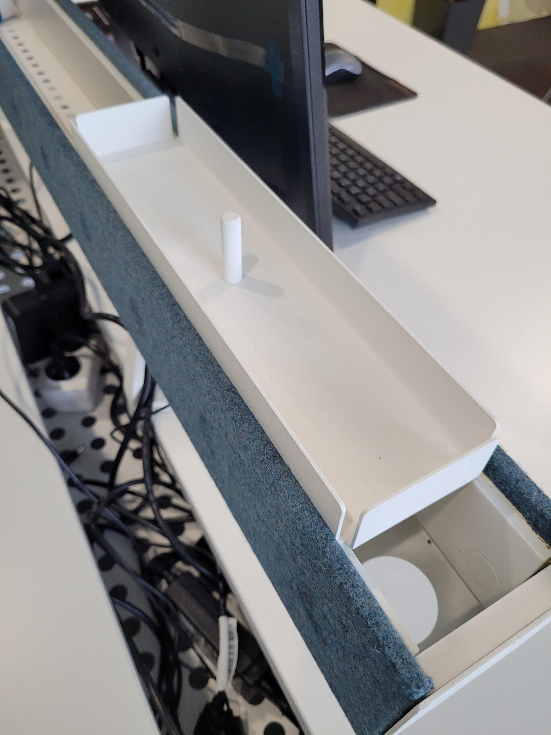 Ergonomiczny system organizacji kabli na biurku z białym organizerem i niebieskim panelem akustycznym