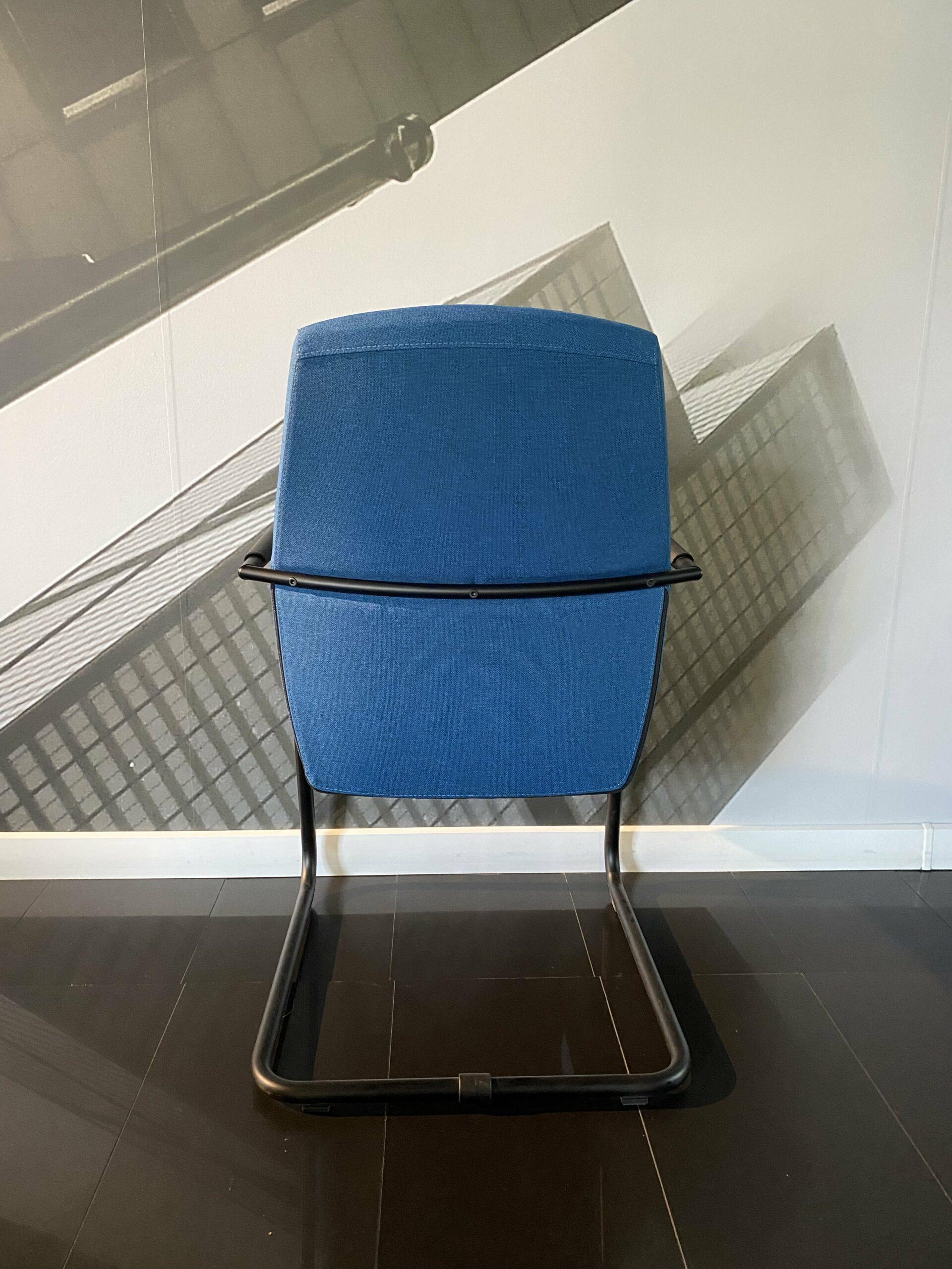 Ergonomiczne niebieskie krzesło biurowe z czarnym stelażem w nowoczesnej przestrzeni.