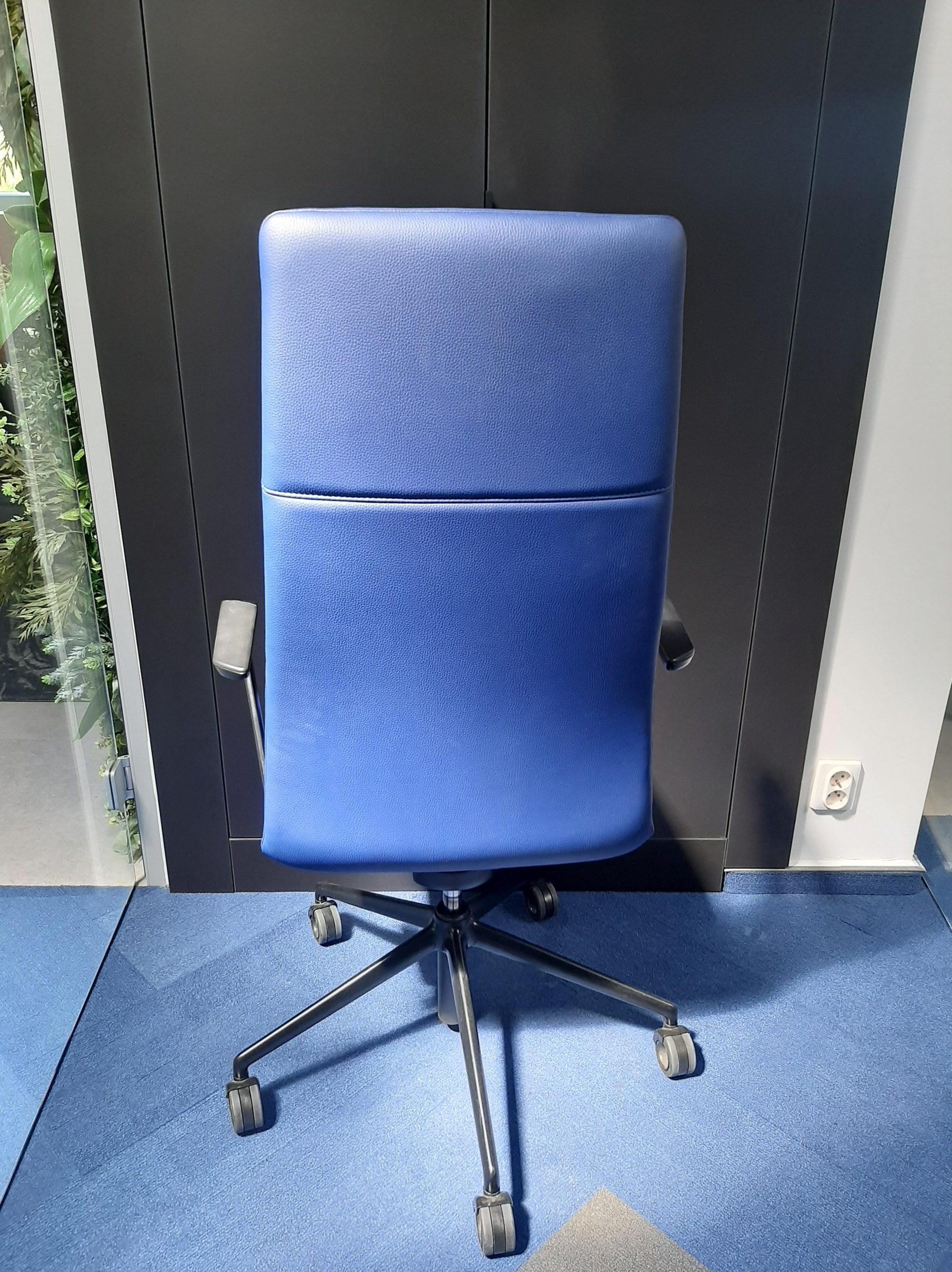Niebieskie ergonomiczne krzesło biurowe na kółkach w nowoczesnej aranżacji przestrzeni pracy.