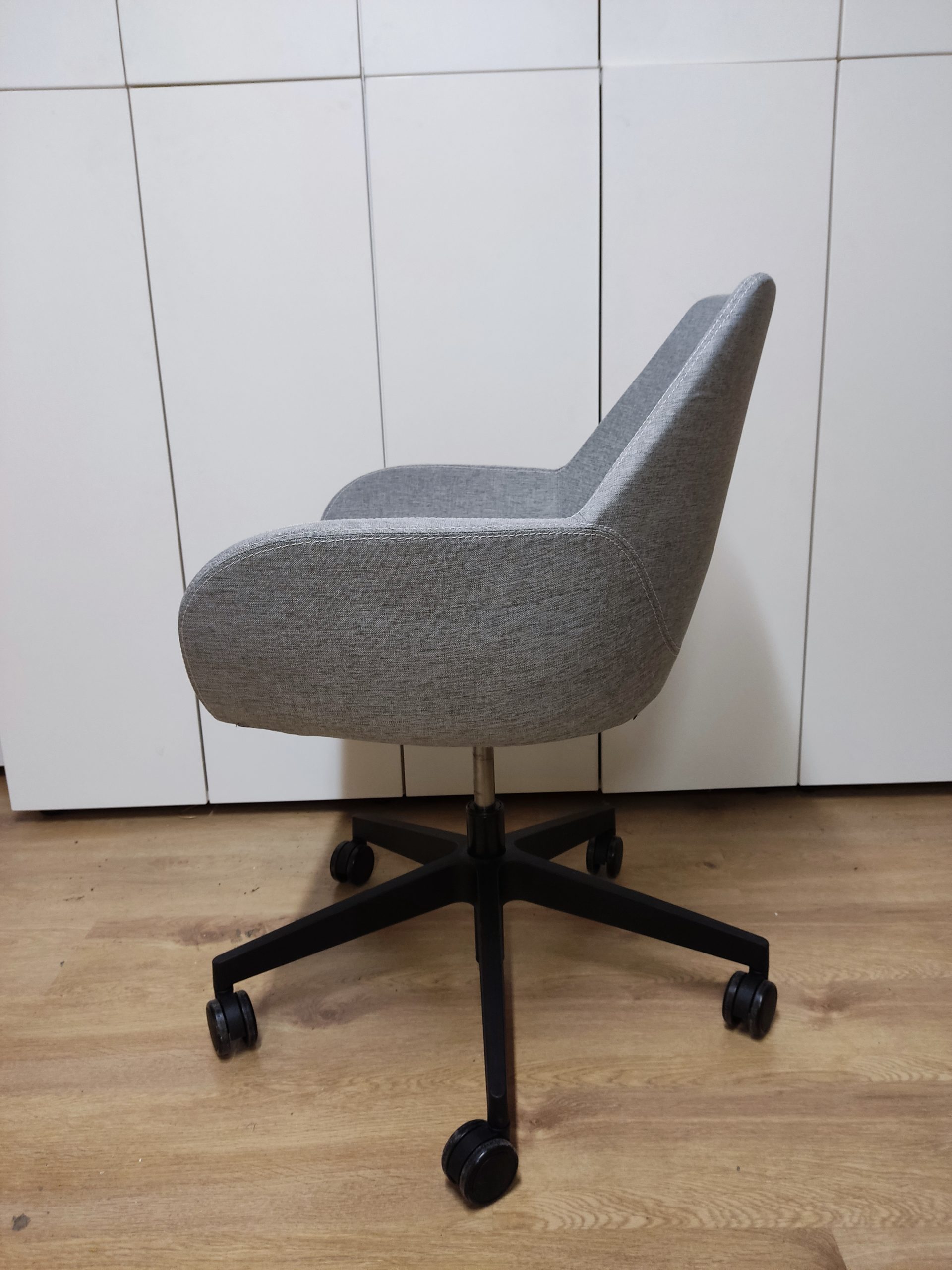 Ergonomiczne szare krzesło biurowe z czarną podstawą na kółkach do nowoczesnych biur.