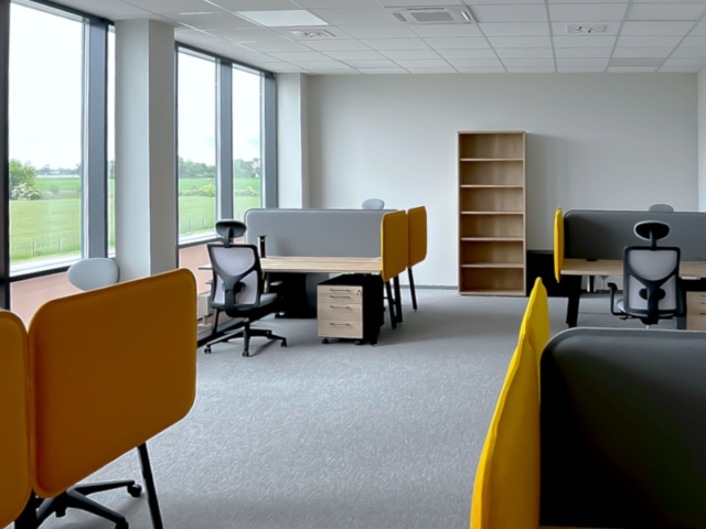 Projekt ergonomicznych stanowisk pracy w jasnym biurze z szarymi i żółtymi przegrodami.