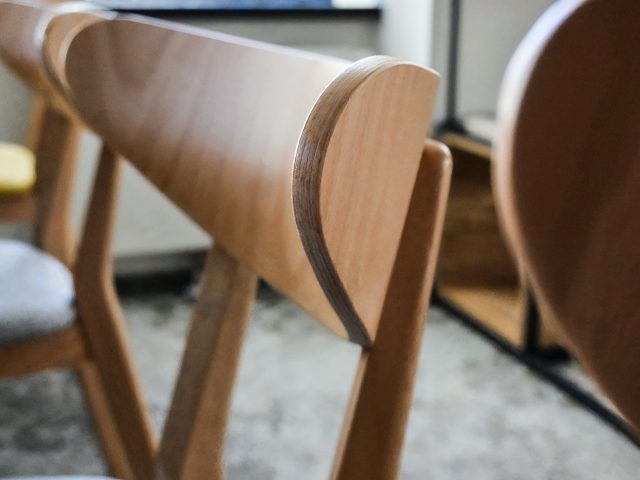 Ergonomiczne drewniane krzesła z jasnoszarymi obiciami w nowoczesnej przestrzeni biurowej