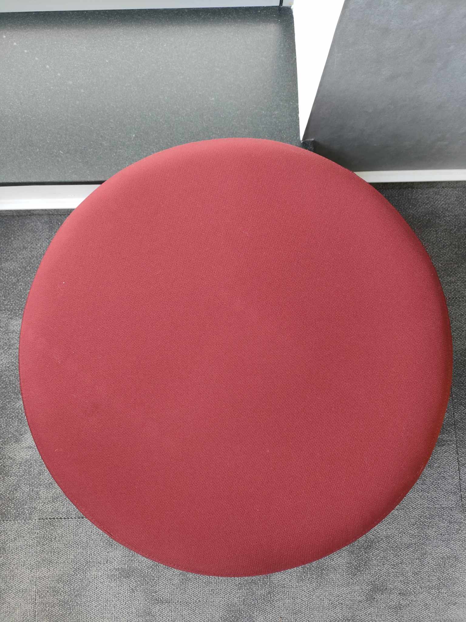 Nowoczesny czerwony puf, element wyposażenia ergonomicznej strefy współpracy w biurze.