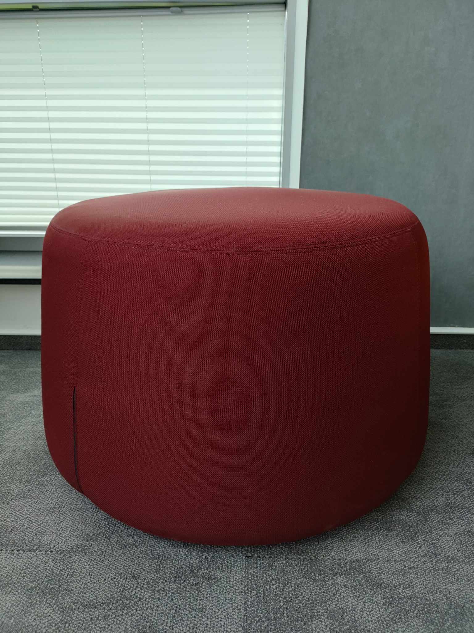 Ergonomiczny czerwony puf do strefy współpracy w nowoczesnym biurze.